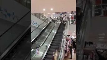 woman falls up escalator