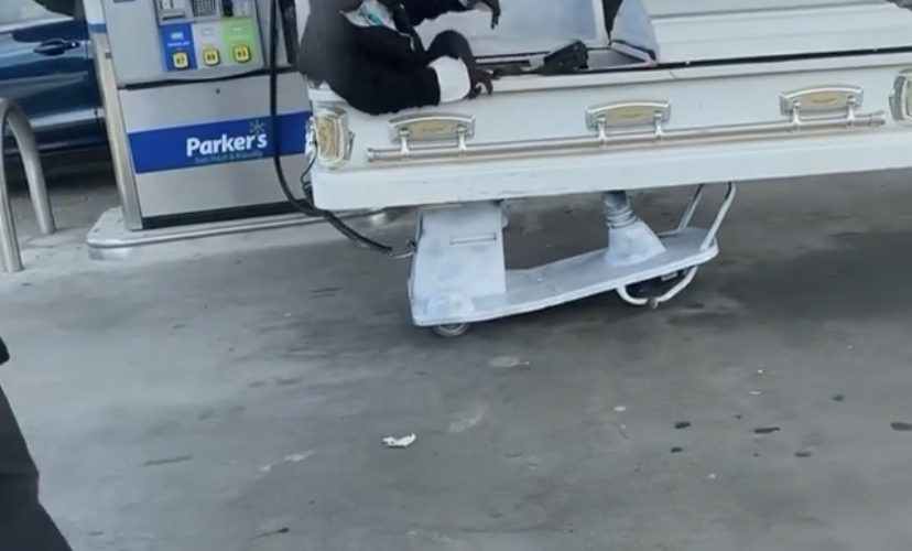 man drives coffin at gas station
