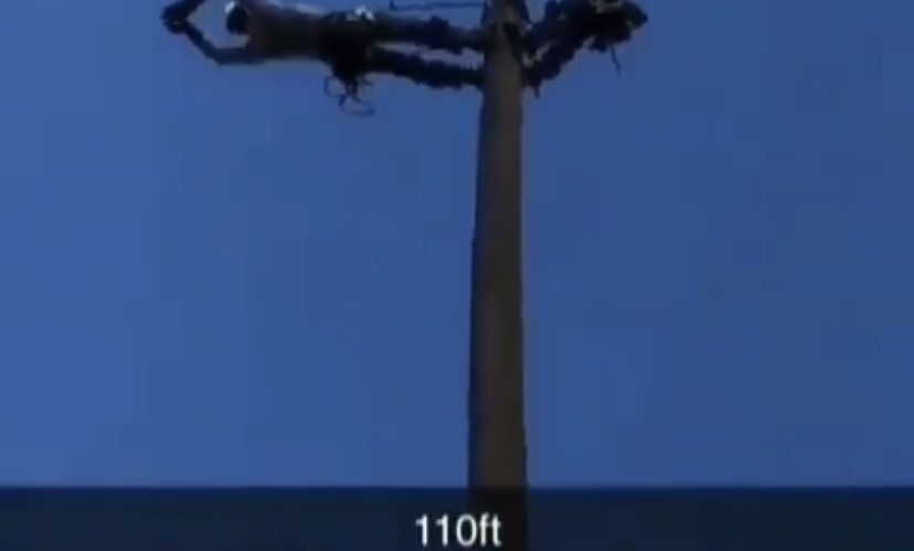 man hangs from pole
