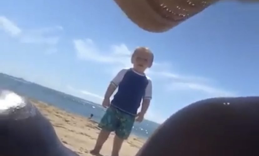 Little boy staring at women on beach