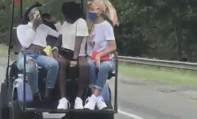 Girls drive golf cart down highway