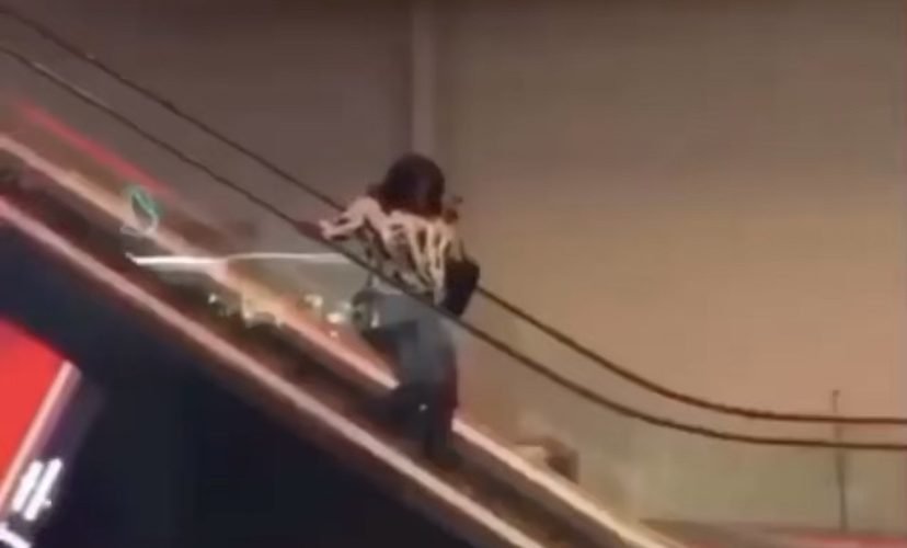 Woman tries to walk down escalator