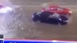 A person drives a supercar through floodwaters
