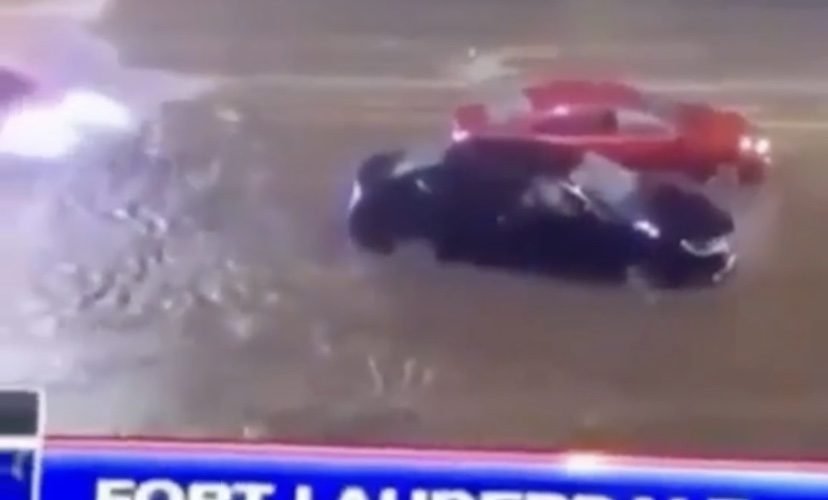 A person drives a supercar through floodwaters