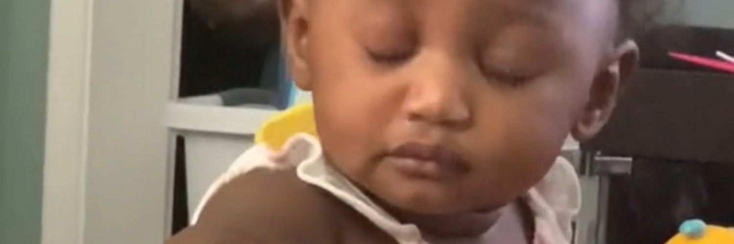 A baby responds to her father coughing while watching TV.